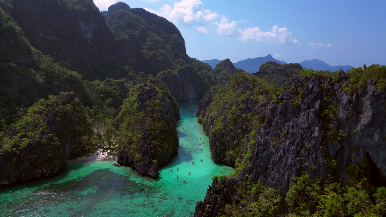 Big Lagoon in El Nido, Palawan showing limestone islands, clear turquoise water, and scenic ocean views. Tremendous aerial view descending panorama drone