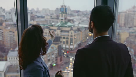 two architects looking city view standing at window high office building closeup