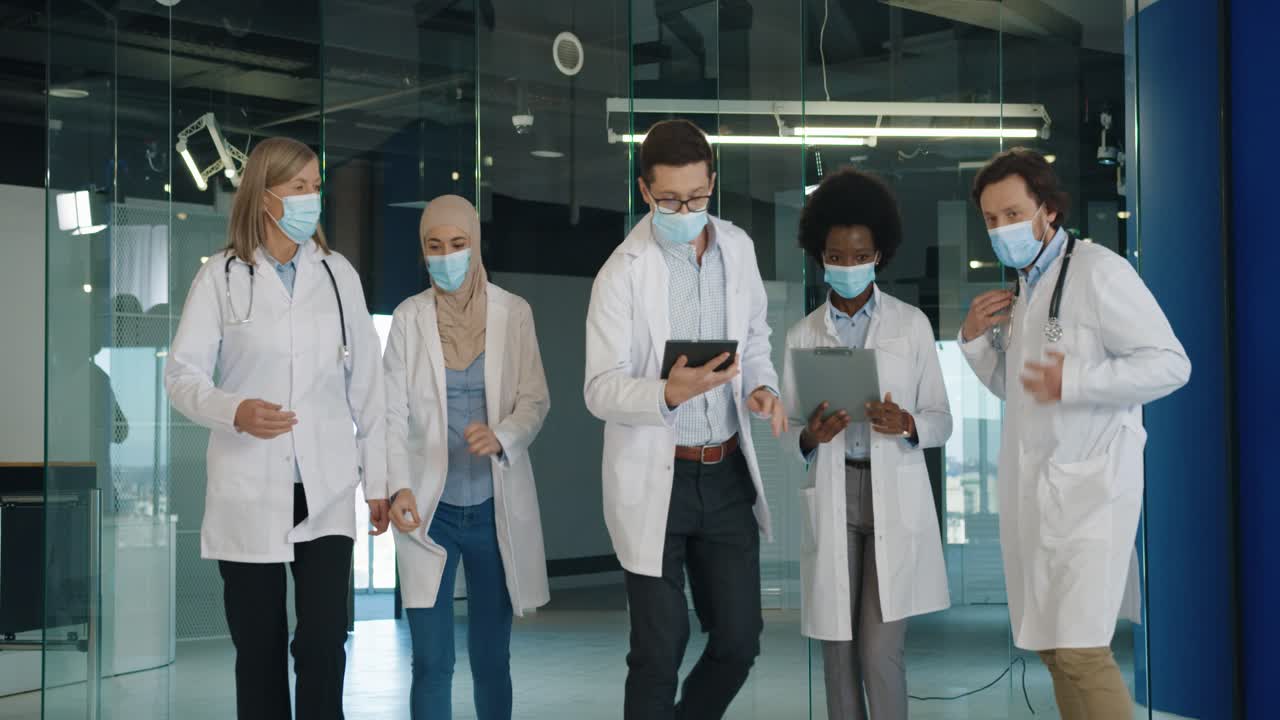 긴급한 상황을 치료하기 위해 병원에서 달리는 의료용 마스크를 쓴 다민족 의사 팀