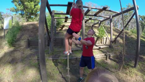 entrenador ayudando a una escolar en escalada de cuerda durante una carrera de obstáculos 4k