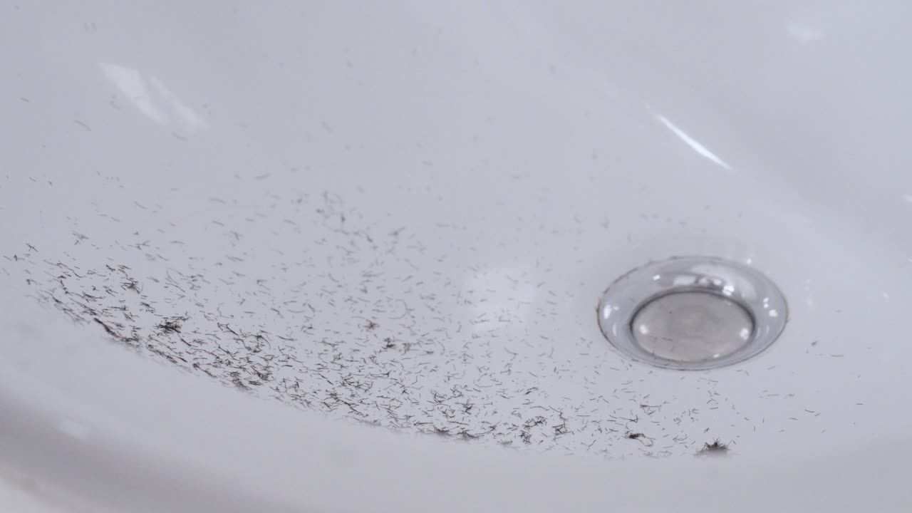 Slow motion view of shaved beard hair falling in the white sink