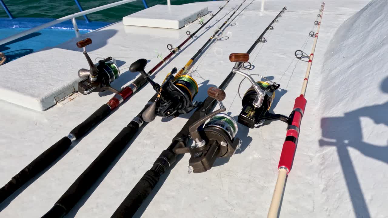 Fishing rods neatly arranged on a boat deck under bright sunlight, set against the backdrop of Phuket's clear blue waters