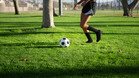 a female womens soccer player running and dribbling a football up the field during a team sports practice slow motion