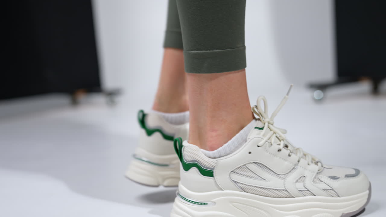 Fitness lady in leggings and comfortable sneakers. Stylish sport footwear close up in studio. Blurred backdrop.