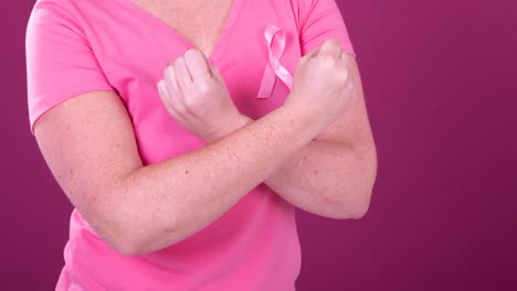 Video-of-midsection-of-caucasian-woman-with-crossed-arms-wearing-pink-cancer-awareness-ribbon