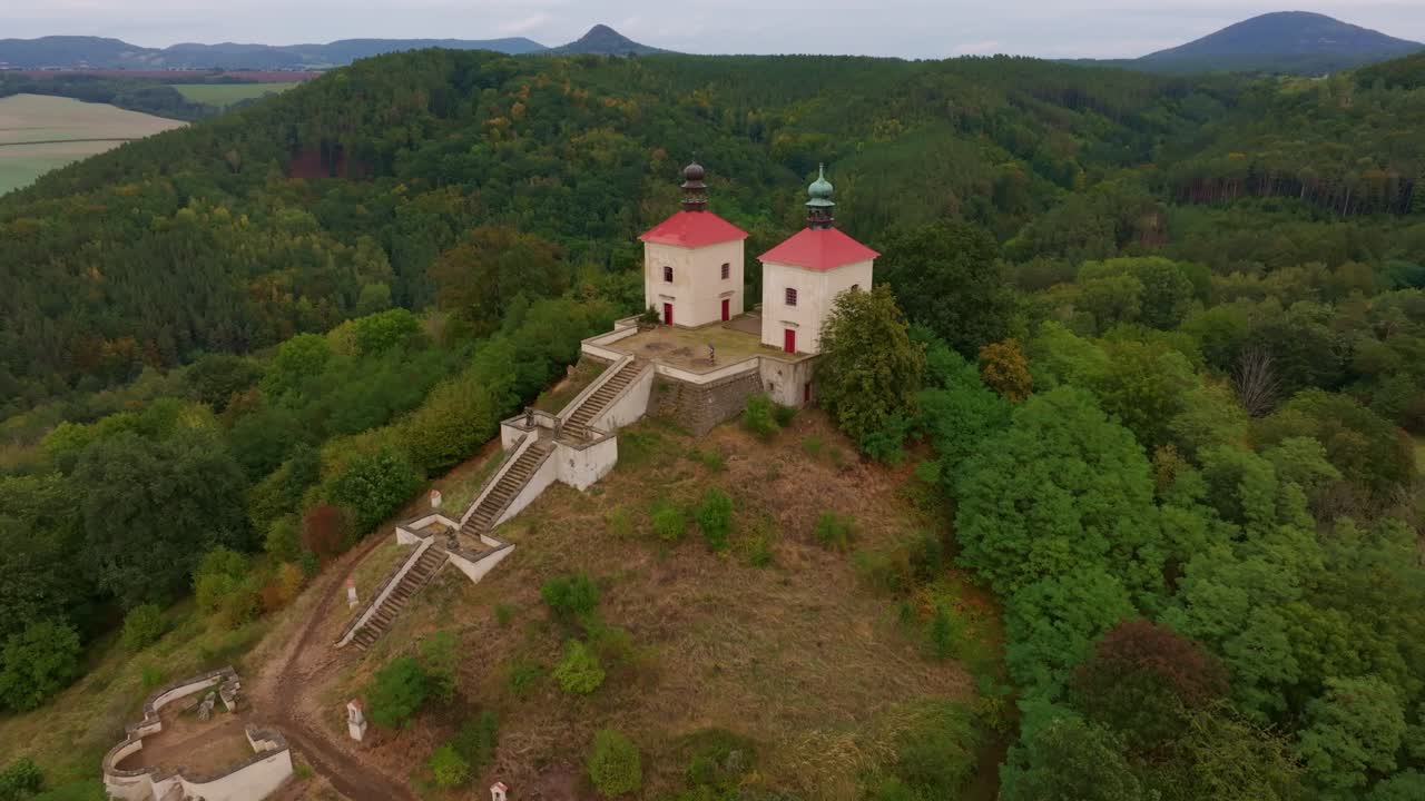 Colline rigogliose e alberi circondano la chiesa del Calvario di Ostre, Ustek, Repubblica Ceca.