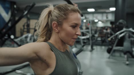 side view of young caucasian woman  exercising with weights  on a gym.