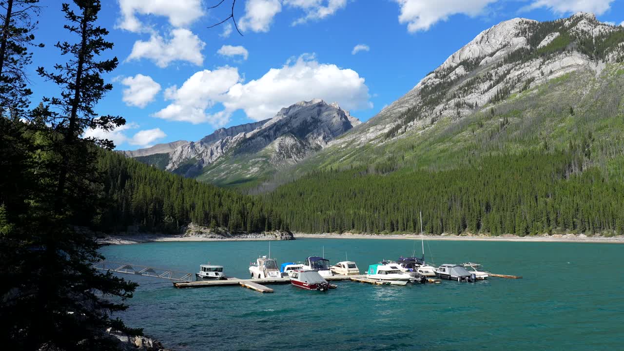 Barche sul lago Minnewanka circondato da montagne e foreste