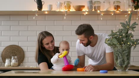 padres con un bebé jugando con un juego de madera