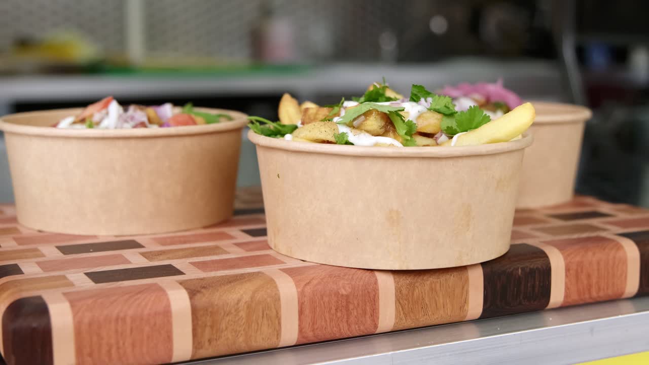 Biodegradable poke bowl ready for customer displayed at food truck with fries, sauce and different Indian dished.