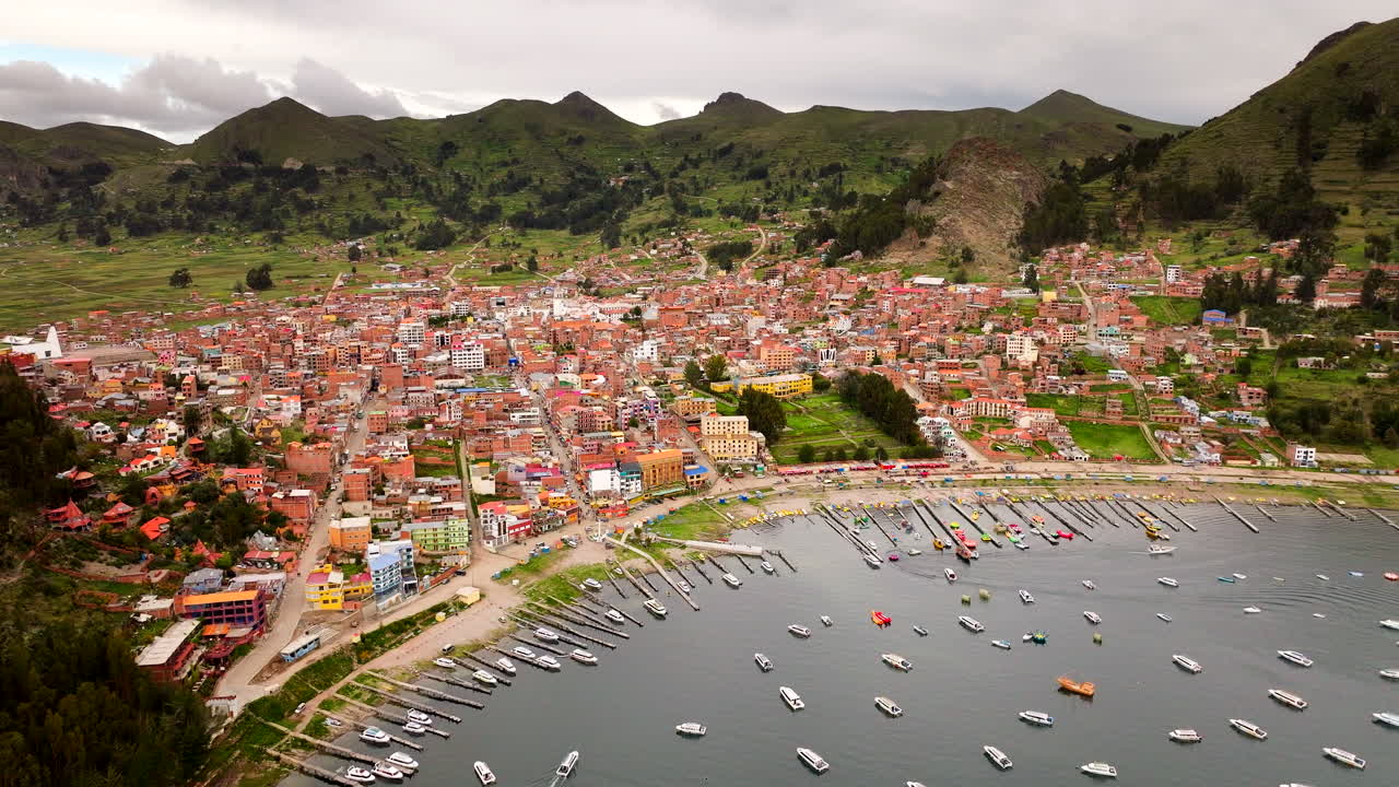 Aerial drone view Copacabana town on shore of Lake Titicaca, Bolivia, harbor with boats and surrounding green hills