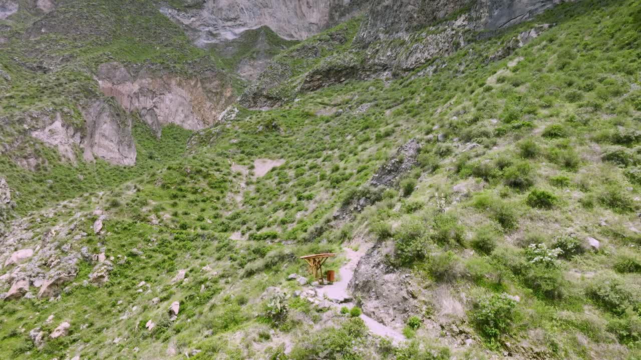Drone shot capturing a resting spot along the ascent of the trekking path towards San Miguel, with hikers taking a break while surrounded by the rugged terrain and stunning views of the Colca Canyon.