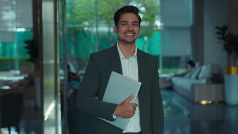 businessman holding a laptop in a hotel lobby