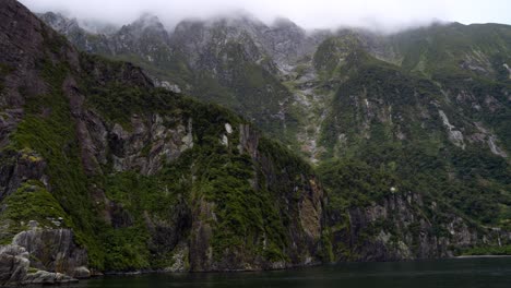 View-of-the-sheer-rugged-mountains-of-the-Milford-Sound-with-peaks-hidden-in-the-clouds