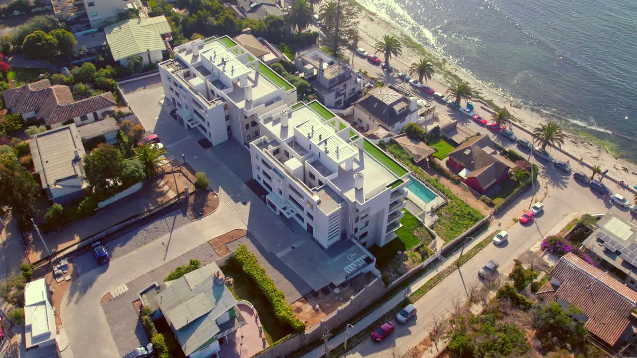 Flyover establishing drone of new residential buildings with swimming pool and ocean view at Los F&oacute;siles beach, Algarrobo, Chile