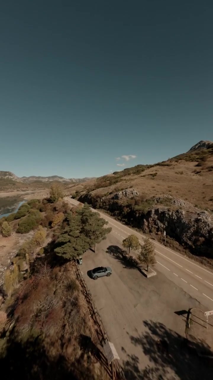 Una ripresa verticale cinematografica con drone FPV che vola sopra il bacino di Porma a León, Spagna, con coste rocciose, riflessi chiari dell'acqua e paesaggi montani.