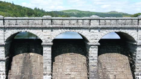 rising aerial reveal of burrator reservoir beyond stone dam with car driving by