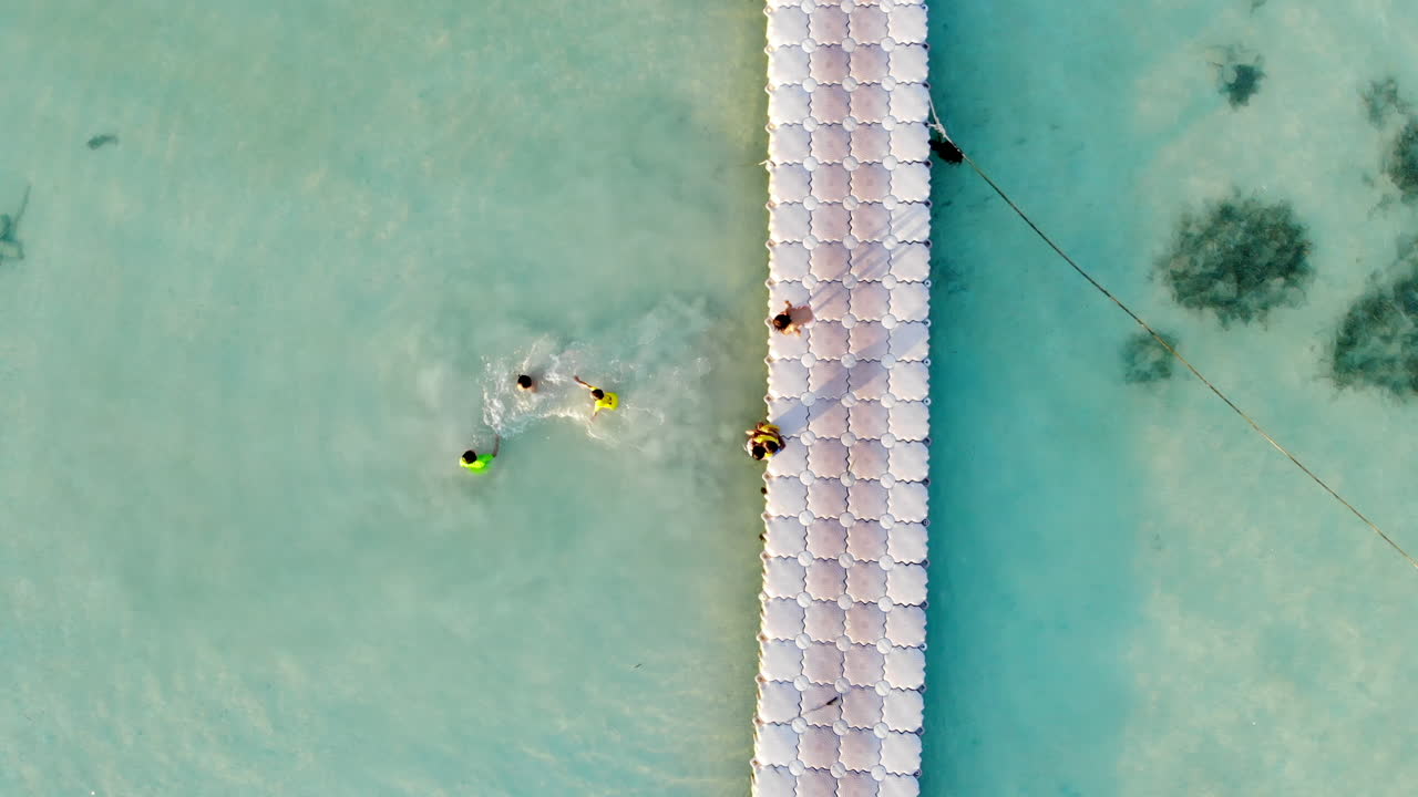 niños jugando en agua clara junto a un muelle
