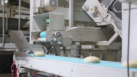 fresh bread dough dropping onto conveyor belt in bread factory