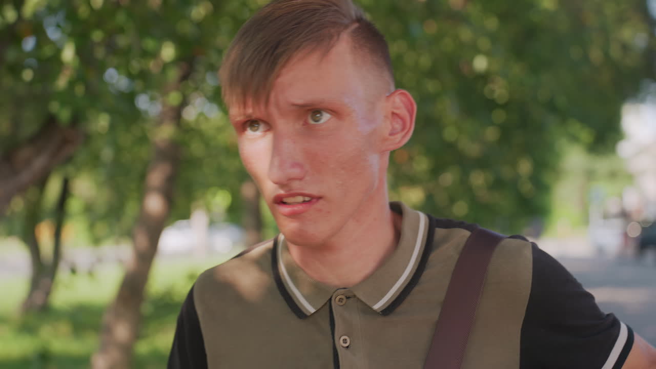Young Man Startled Reacting To Unseen Noise On TreeLined Street, Sharp Facial Expression, Quick Head Turn, Hands Reach For Bag Strap, Tense Jaw, Candid Emotional Moment In Daylight