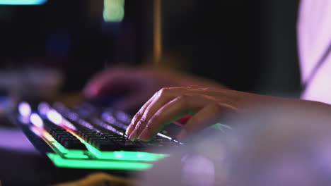 close up of teenage girl with hands on illuminated keyboard gaming at home at night