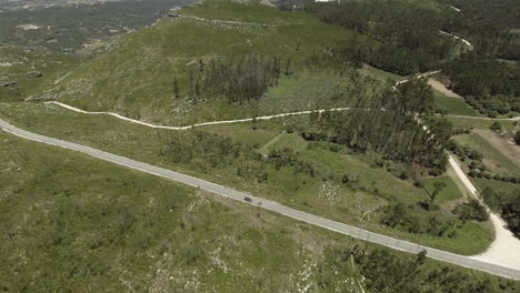 Car-Driving-On-The-Long-And-Winding-Road-Through-Lush-Fields-In-Reguengo-Do-Fetal-Route-In-Batalha,-Portugal---aerial-drone