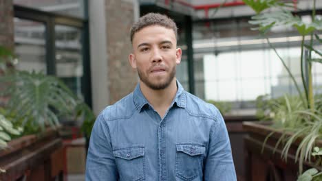 retrato de un hombre biracial sonriendo en el balcón de la oficina