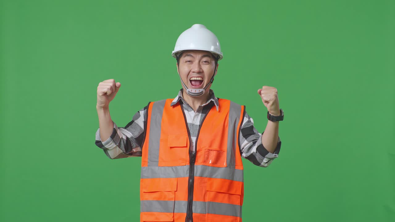 Asian Male Engineer With Safety Helmet Screaming Goal Celebrating Working In The Green Screen Background Studio