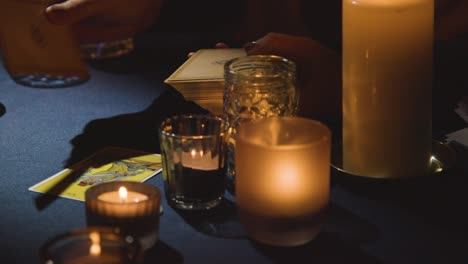 nahaufnahme einer frau, die tarotkarten bei kerzenlicht auf dem tisch 1 liest