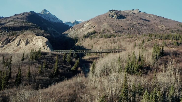 Il drone prende quota per mostrare un ponte ferroviario e una montagna in Alaska