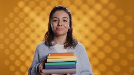 Portrait-of-smiling-woman-holding-stack-of-books,-doing-salutation-hand-gesture