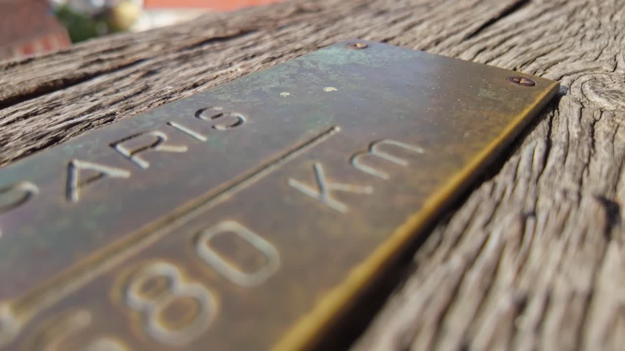 Close-up of a metal plate indicating the distance to Paris, France from the Clock Tower in Sighișoara, Romania