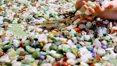 excited european kid collects bunch of gemstones in hands and spill them again