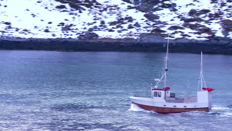 un barco de pesca se dirige a través de los fiordos en las islas lofoten del ártico noruega