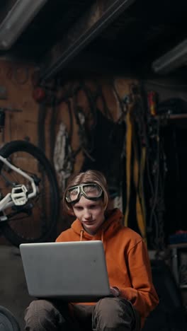 teenager working on a laptop in a garage