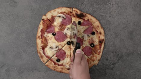 man's hand cutting the pizza