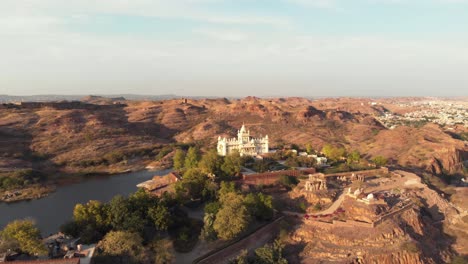 aerial footage flying towards a large palace, brightly lit by by a sunset, on top of a hill of jodhpur, india