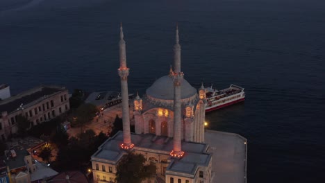 illuminated ortakoy mosque from above at dusk, aerial birds eye view perspective