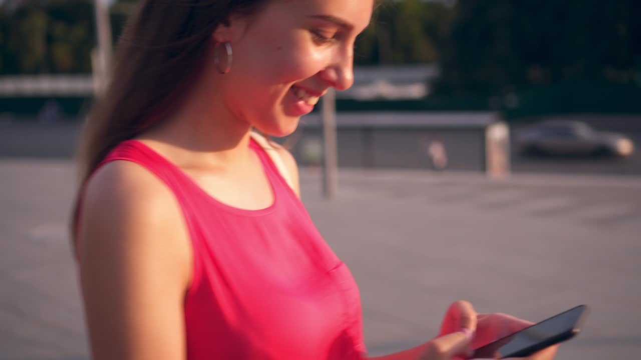 adolescente moderno enviando mensajes de texto en su teléfono inteligente al atardecer en la ciudad
