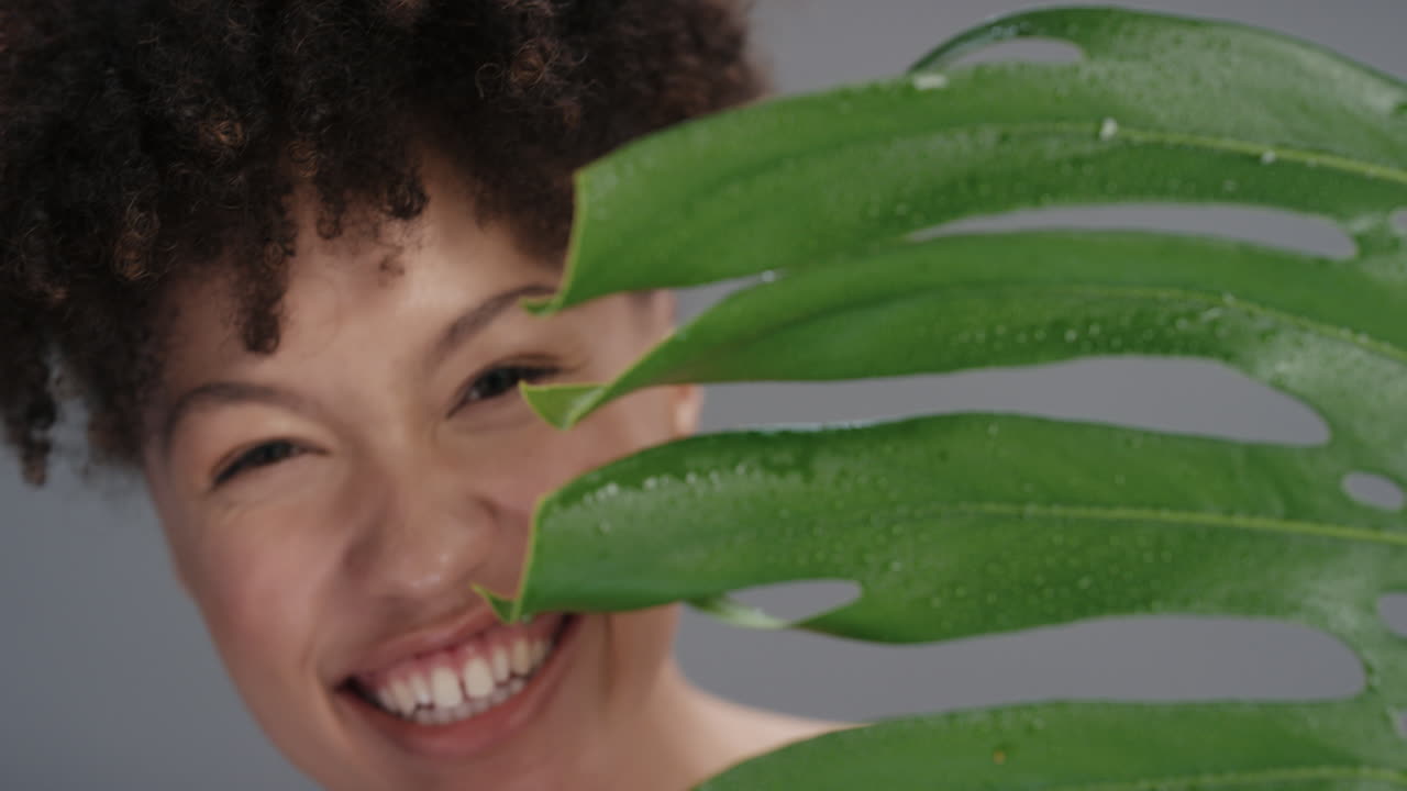 가까운 초상화 아름다운 여성이 식물 뒤에 숨어 놀이하는 부드러운 자연 피부 피부를 가진 매력적인 여성 건강한 피부 관리 아름다움 개념을 즐기고