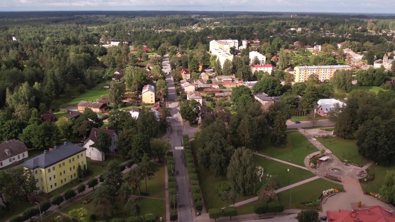 Un drone cattura una vista aerea della piccola città di Valka, mostrando i suoi edifici, le strade e la vegetazione circostante. Il paesaggio urbano pacifico contrasta con la bellezza naturale della zona.