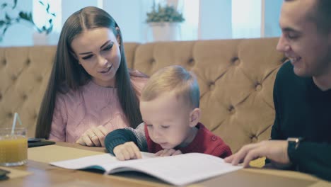 una dama habla con un niño con un libro cerca de un hombre bastante guapo