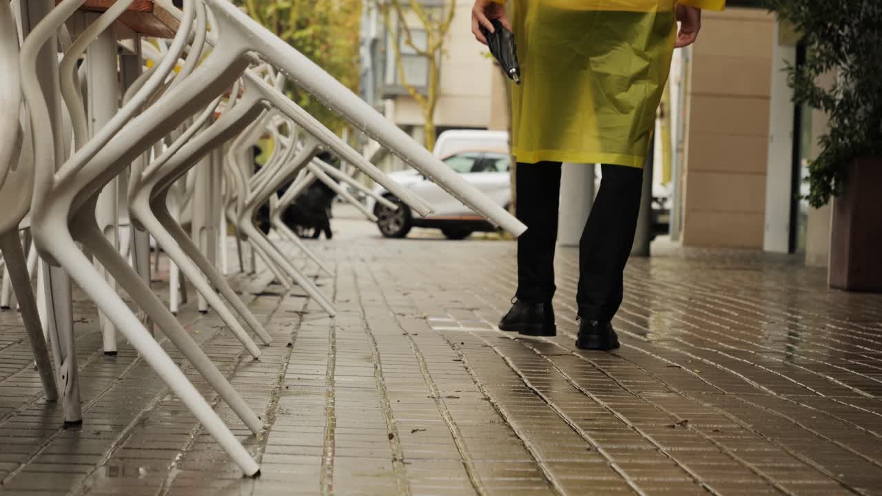 Business man tourist person with umbrella and raincoat on rainy european city street, lights reflecting, walking in Barcelona or Amsterdam during the rain