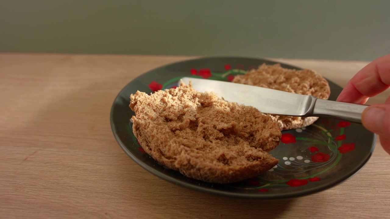 Hand cutting brown wholemeal bread for sandwich close up zoom slow motion shot selective focus