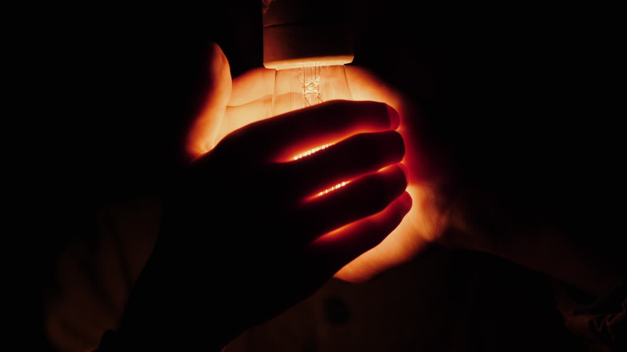 한 남자가 전구 주위에 손을 잡고 있다