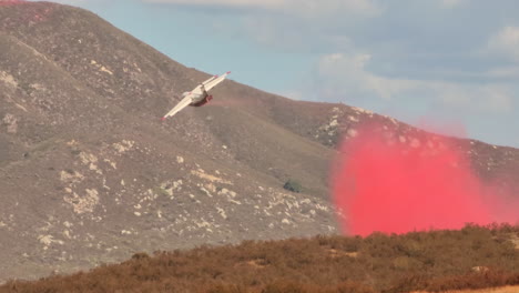 un avión arroja un retardante de fuego rojo sobre un incendio forestal en fairview en california