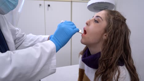 médico masculino examinando la garganta del paciente en la clínica