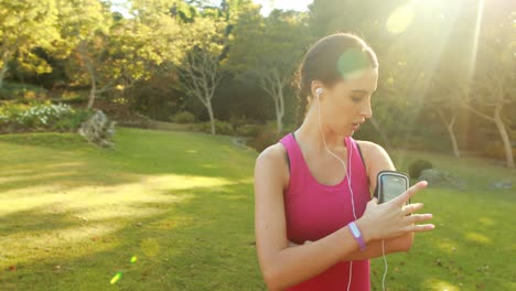 woman adjusting music settings on armband from smartphone