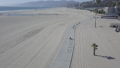 aerial drone shot of 5 people on bikes riding on beach boardwalk