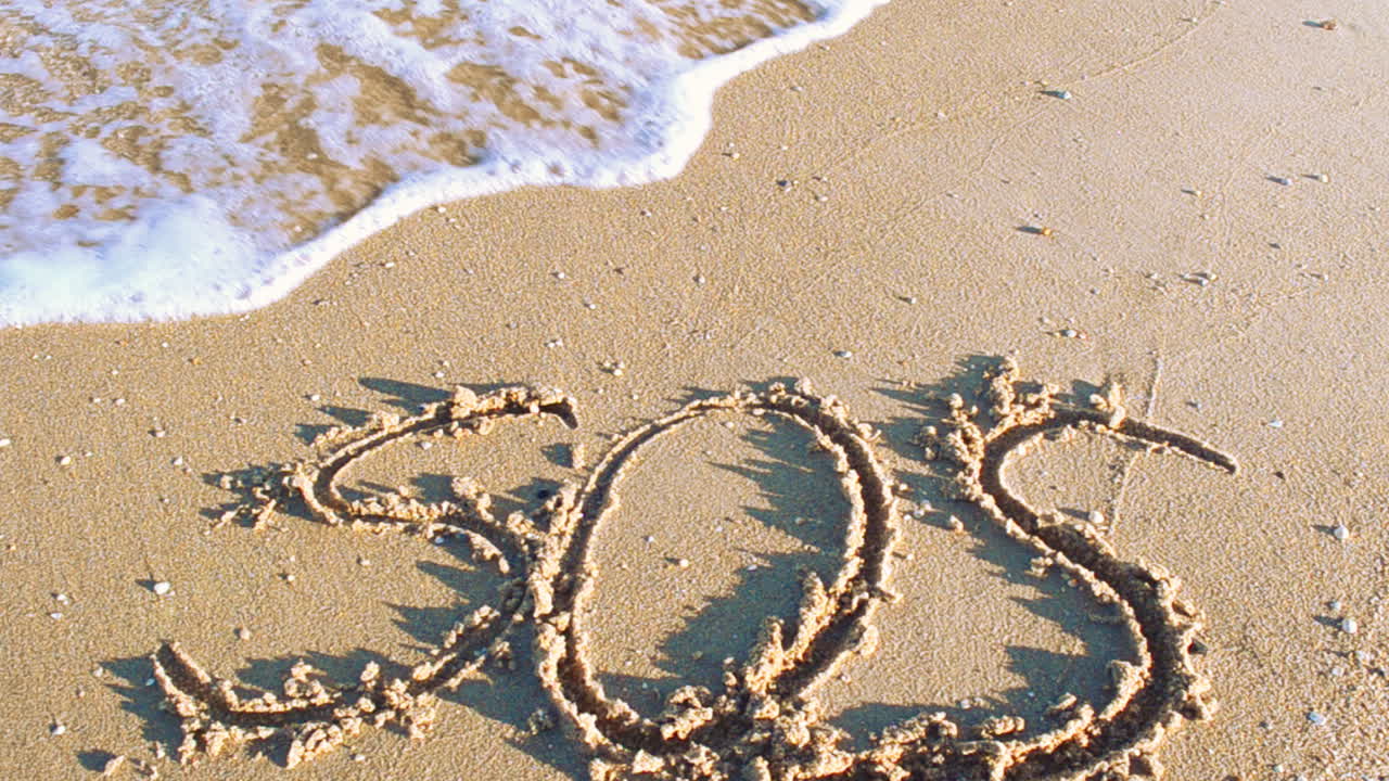 The inscription SOS on sand. The inscription is written with a stick
